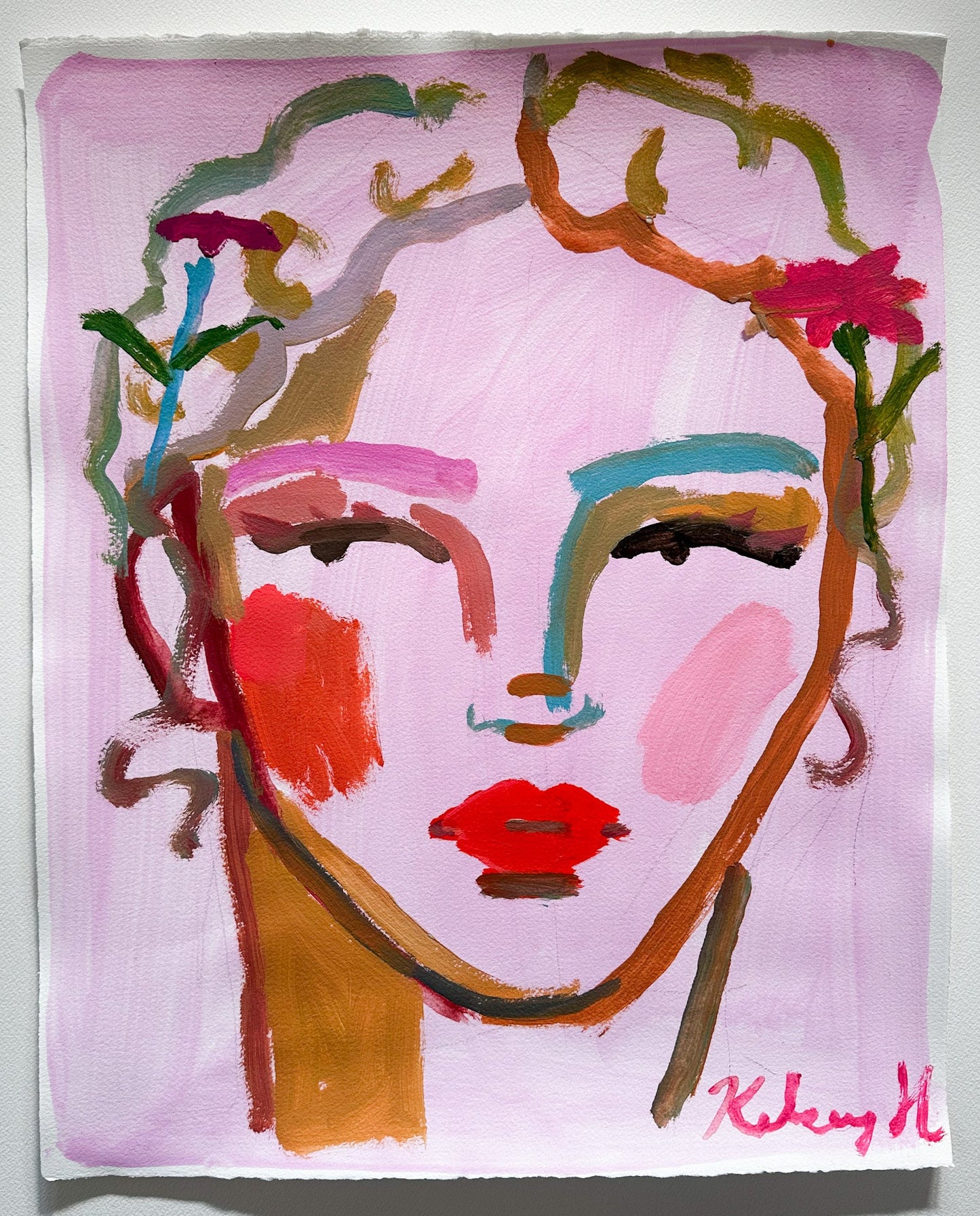 Abstract art piece with colorful face design on a pink background