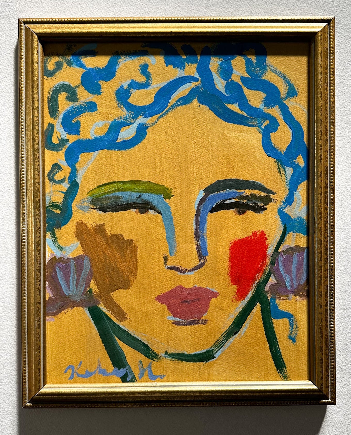 Framed artwork of a stylized face with blue hair and colorful makeup on a yellow background.